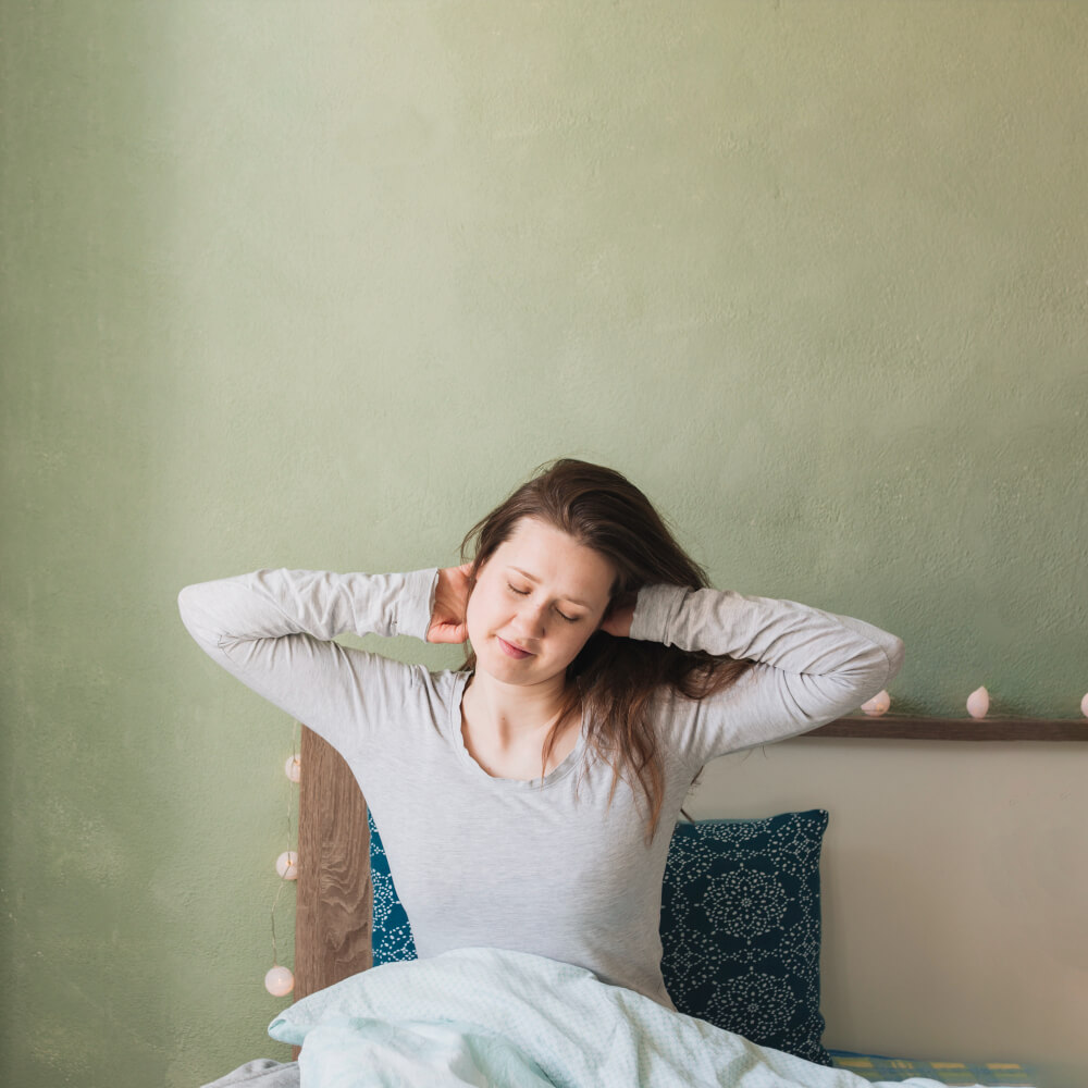 Woman relaxing in her bed, benefits of being a morning person